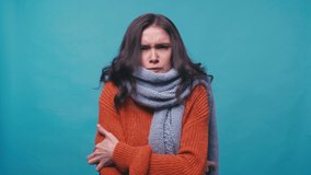 sick woman in scarf freezing and sneezing isolated on blue