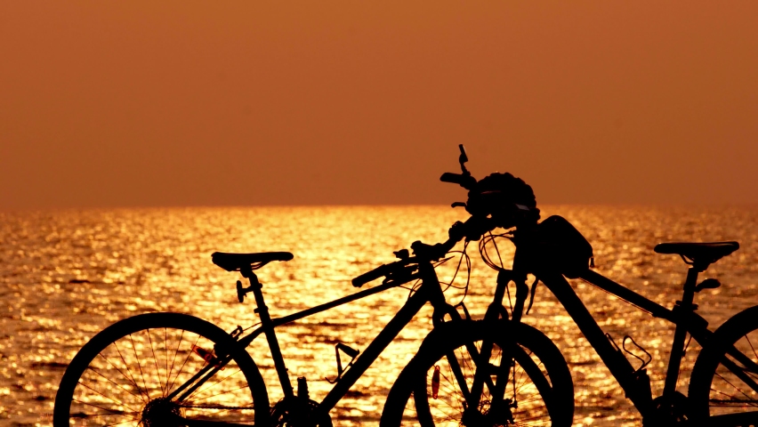 beautiful sunset view behind mtb, mountain bike, bicycle silhouette near ocean and beach with helmet for exercise outside in nature sunset time with wave and sea view Royalty-Free Stock Footage #1067082670