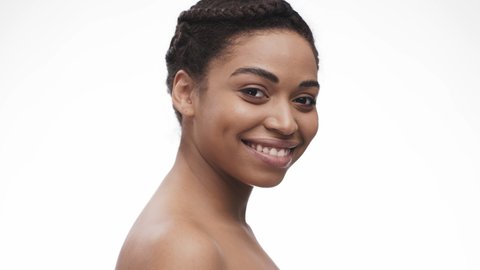 Beauty care concept. Back view of young nude african american lady turning to camera and smiling, white studio background