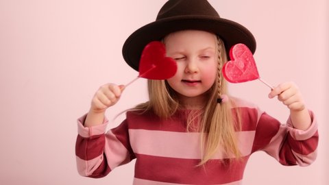 Little kid girl holding red heart shape candy and dancing. Valentine's day and love concept.