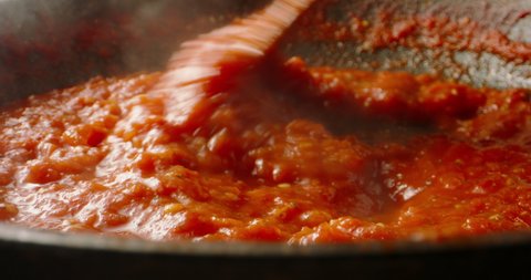 Tomato sauce boiling in a pan, being stirred with a spoon. Hot tomato sauce cooked for pizza or pasta. Italian cuisine, food and drink 4k footage