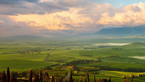 Time lapse of the morning fog and clouds moving over the rolling green hills of Tuscany Italy.