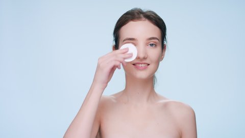 Young fresh looking brunette woman and beauty model demonstrates easiness of applying skin care product using a cotton pad | Skincare and clear skin concept