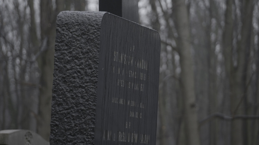 Camera tilts down slowly upon an old Jewish, black gravestone on a gray, rainy, winter day. a 4K (Sony S-Log) clip, February 23rd, 2020, Warsaw, Poland.