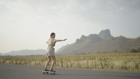 4k Video slow-motion side camera view, Adult Asian women surf skateboarding on the streets outside country road with mountain views in the evening. lifestyle concept.