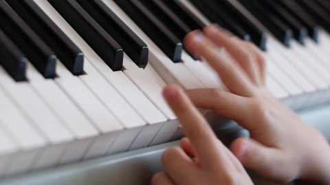 The child plays the piano theme. Close-up of fingers of a boy learning playing the piano. Creativity in children. Playing the piano. Selective focus, shallow depth of field