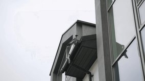 Crow sits on black roof of house on drain pipe, pecks at food and then runs away - Powered by Shutterstock - Get 15% off with code: PIKWIZARD15