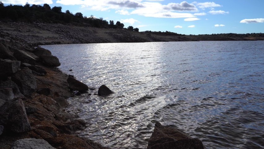 Lake landscape with water moving by the waves and reflections of the sun making star flashes.
