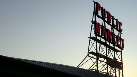 SEATTLE, WASHINGTON, USA – 29 JULY 2019, Time lapse video of the sun setting behind the public market sign at Pike Place Market, Seattle, Washington, USA