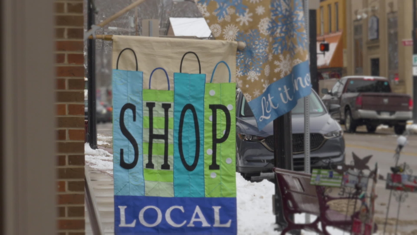 A view of a Shop Local flag outside a small business on the main street of a Pennsylvania town during the Christmas season. Pittsburgh suburbs.  	