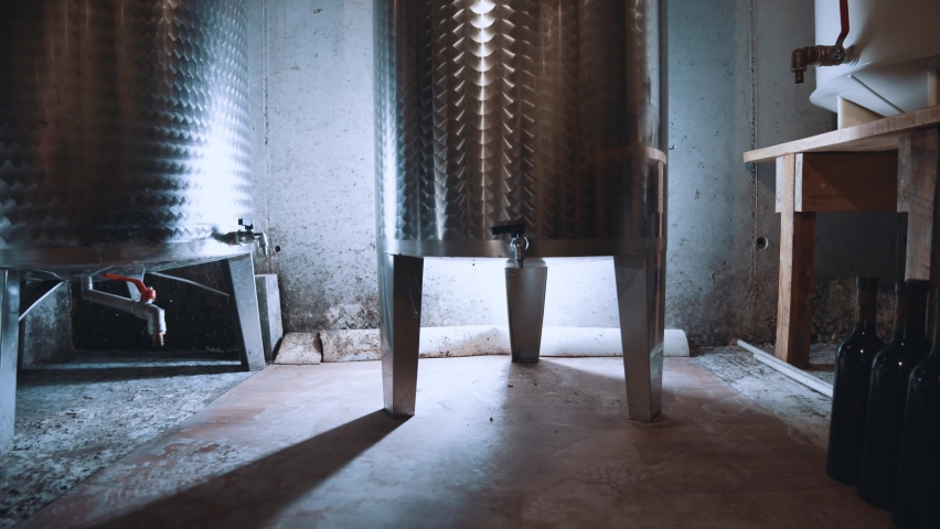 Wine production step by step. at the wine factory. Low angle motion camera view at the big metal barrels with taps and wine inside it. Zoom out shot. Alcohol manufacturing concept. Stock video