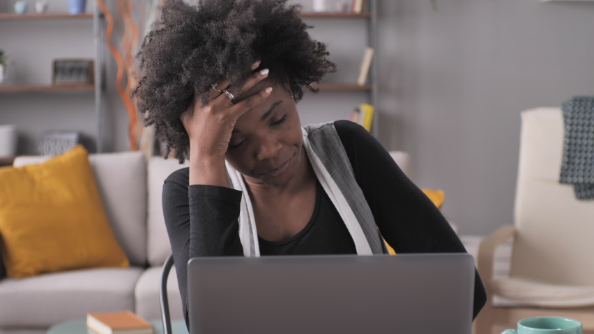 Frustrated angry black woman entrepreneur working at the computer from home,young african american female sitting at her desk using laptop looking at the screen in anger | Shutterstock HD Video #1067114584