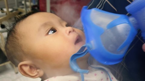 Asian baby getting asthma treatment using nebulizer at clinic