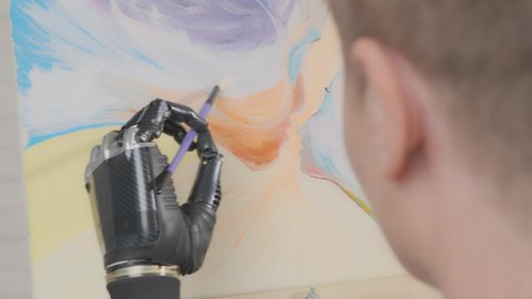 Talented people with physical disability enjoy life doing creative work. Woman artist with disabilities with prosthetic arm draws picture.