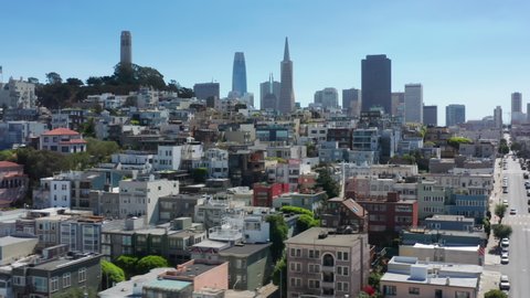 Scenic San Francisco city aerial background. World famous Coit tower landmark and modern downtown skyscrapers on moving background. Vibrant colorful historic victorian buildings architecture on hill