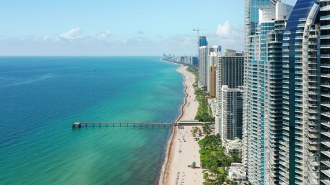 Cinematic aerial Miami beach. Sunny summer day with copy space on blue green background. Travel business footage, drone 4K. Florida vacation USA. Modern water front buildings with beach and ocean view: film stockowy