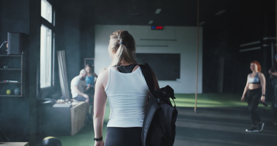 Lifestyle fitness community club. Camera follows young sporty blonde woman enter modern gym, high-fiving happy friends. | Shutterstock HD Video #1067124193