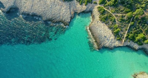 Cove in Menorca with turquoise ans transparent water next to a forest on the island 4K