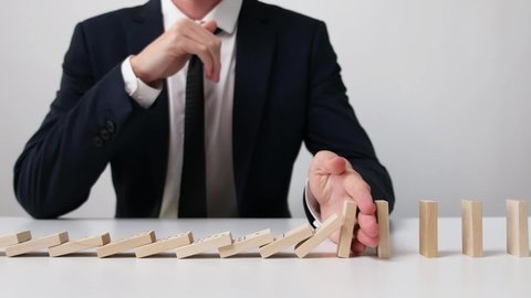 Businessman Stopped the Falling Domino Effect. Slow Motion.