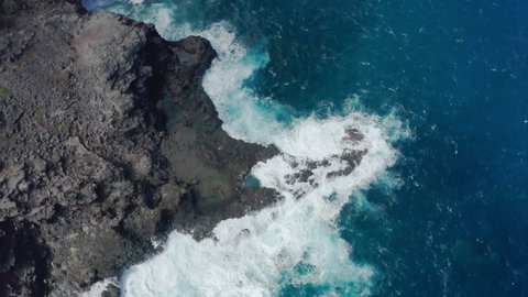 Overhead view, drone rotating and circling above men and women swimming in stormy blue Pacific ocean. Hawaii island, Maui. Aerial 4K people relaxing at beautiful natural volcanic pools on summer day