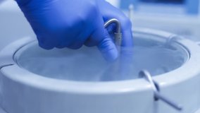 Laboratory worker get Cryogenic container with reproductive cells, Haze and fog comes out from the freezing container. Liquid nitrogen freezer vaccine storage. medical cryogenics biotechnology. - Powered by Shutterstock - Get 15% off with code: PIKWIZARD15