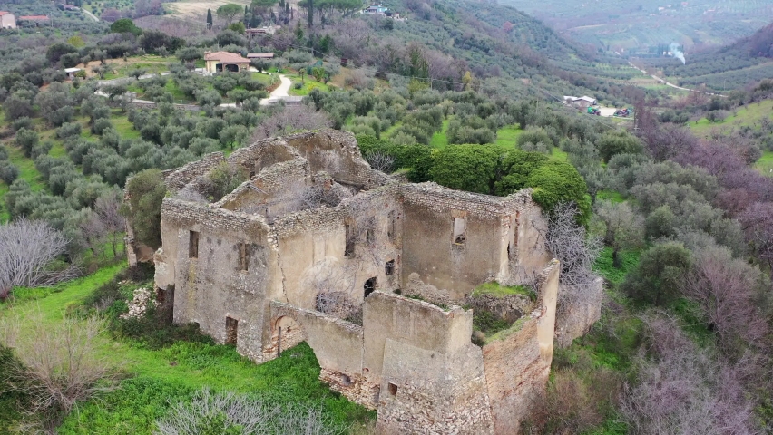 Ancient ruined ruin on top of the hill.
Aerial view. Drone shot of the hill with olive trees.