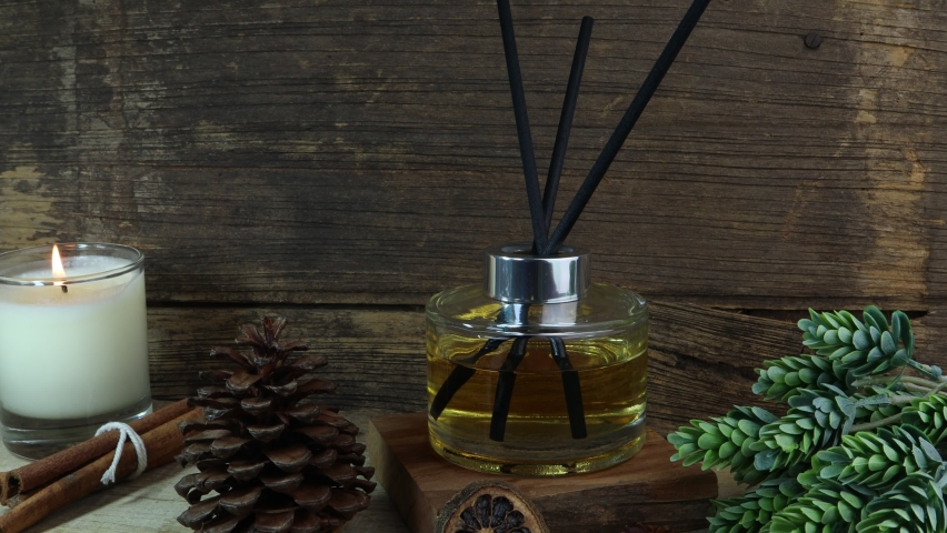 nice aromatic scented reed diffuser air freshener bottle on wooden table with pine cone and background of old vintage wooden texture wall of living room to creat realx ambient in cottage for christmas