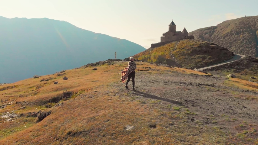 A female person stands alone on a hill thoughtful and enjoying nature while traveling. Concept of personal well being.