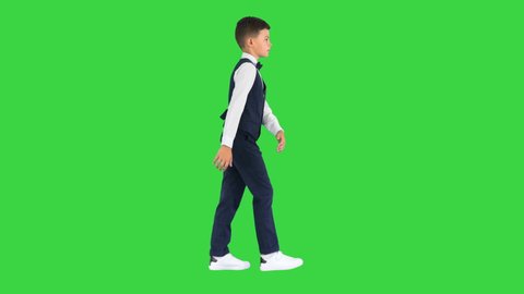 Little boy in a bow tie and waistcoat walking waving his hands on a Green Screen, Chroma Key.