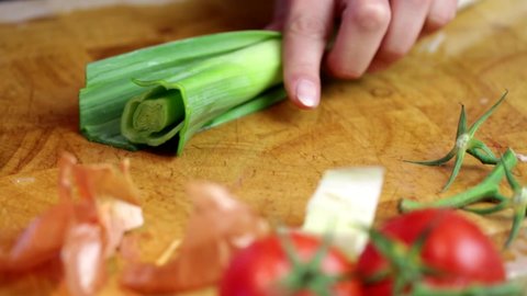 Cutting up leeks on a chopping board with tomatoes