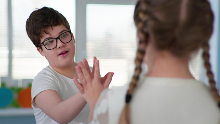Child development, cute male child with disabilities holds hand in hand girl during lesson in an inclusive school | Shutterstock HD Video #1067158063