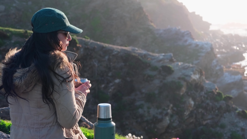 woman drinking yerba mate, typical Argentine drink, on the beach, while watching the sunset pichilemu, punta de lobos, beach for surfing, chile