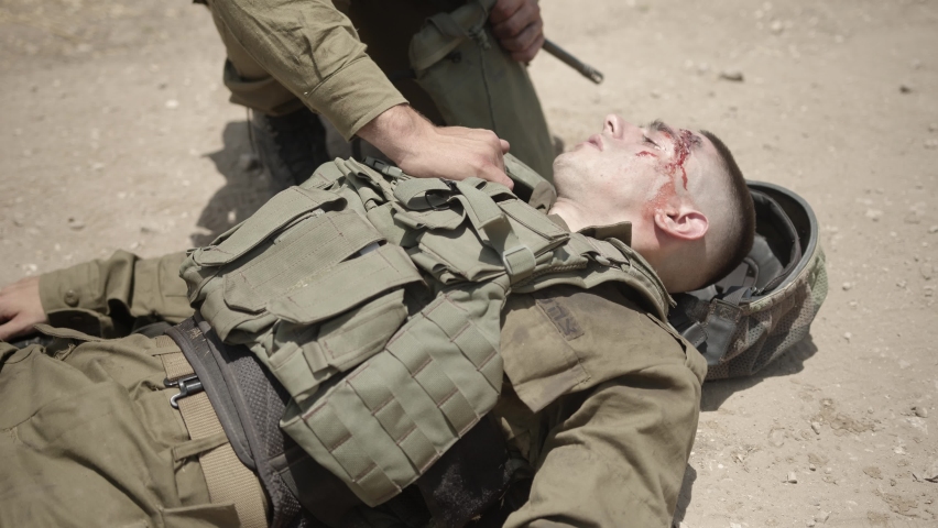 Army infantry soldier carrying his wounded fellow warrior, while another soldier is securing them. Wounded combat soldier is carried to safety.Severely wounded soldier
