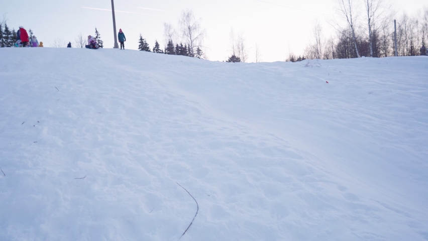 loving family has fun while tubing in the amusement park of a mountain resort. Mother and children ride, sliding down a snow slide. The concept of the winter holidays.