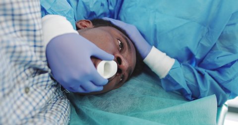 The Doctor Performs Endoscopy Through The Mouth Of A Young African-American Guy, Inserts A Tubular Gastroscope. Apparatus For Endoscopy And Manipulation In Otolaryngology. Modern Equipment Operation