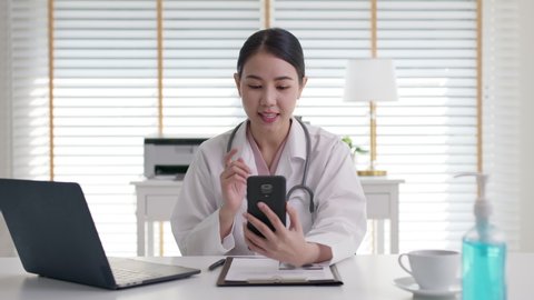 Attractive beautiful asia chinese female doctor video conference call online live talk follow up remotely in medical coronavirus result with patient at office. Online telehealth telemedicine service.