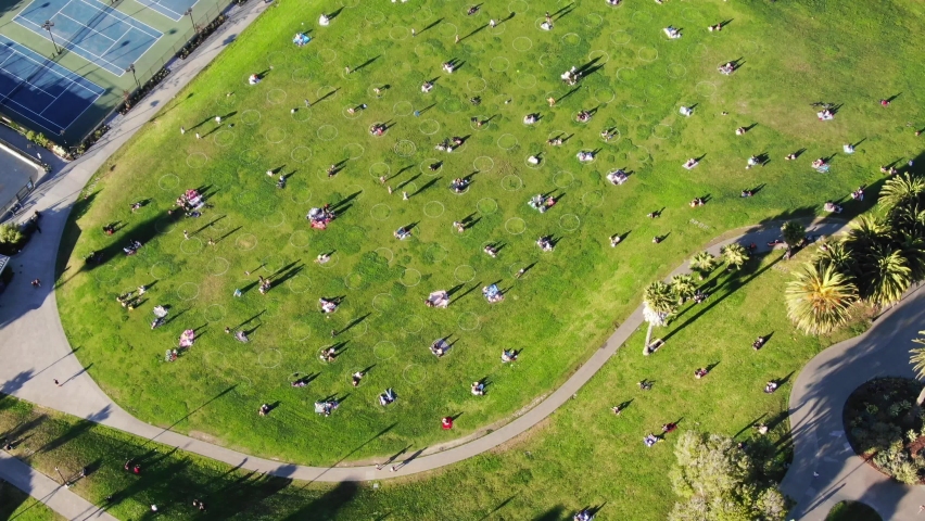 Drone of San Francisco park with 6 foot circles painted for social distancing with zoom to skyline