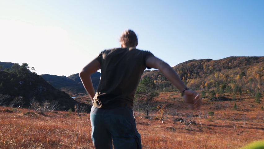 Man bursting with joy, running over dry meadow, jumping up in the air.