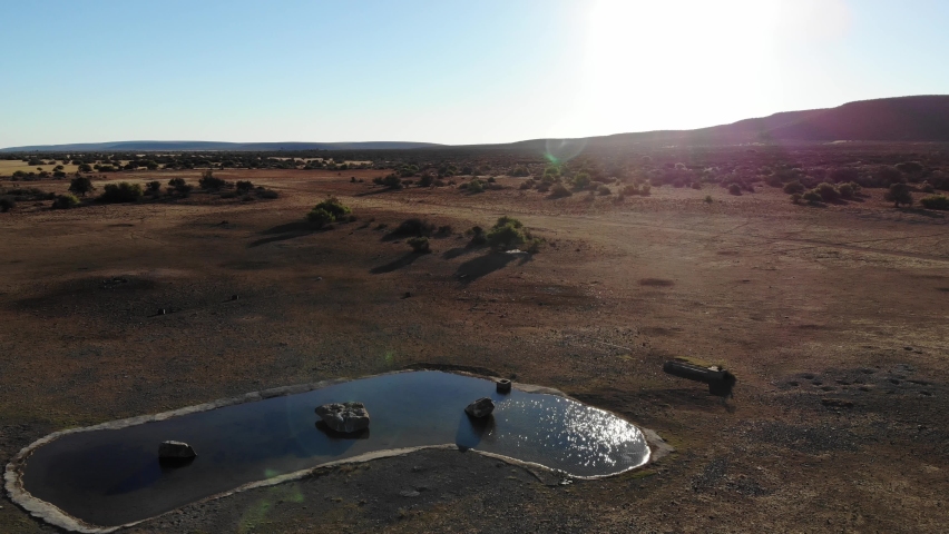 Pan down of a watering hole in Africa looking into the sun