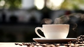 Coffee cup and coffee beans with natural steam smoke of coffee on wooden table, slow motion. Hot Coffee Drink Concept. - Powered by Shutterstock - Get 15% off with code: PIKWIZARD15