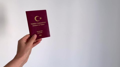 Hand holding Turkish passport on a white background. Turkish standard red passport. Female hand showing a turkish passport.