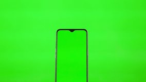 Using a Green Smartphone Screen on a Green Background. The Male Hand Slides Flips Swipes Touches the Phone with the Green Screen, Close-up. Digital Technologies.