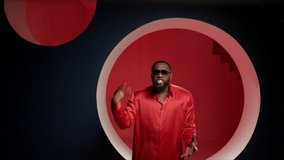 Slo-mo African for music video. African American man dancing in the studio in a bright image. Portrait of a handsome guy dancing on a red background in a good mood. The expressive dancer moves