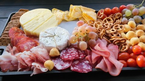 Charcuterie and cheese platter.  Appetizers tray with assorted meat, cheese, fruits, olives and crackers. Arkistovideo