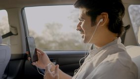 close side view shot of a young smiling Indian male entrepreneur having a video call conversation on a mobile phone while sitting in a rear seat of a moving car