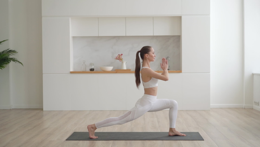 Young attractive multi ethnical woman wearing white sportswear, pants and top, doing stretching yoga exercises on fitness mat in living room, healthcare and exercise mental therapy at home concept | Shutterstock HD Video #1067218144