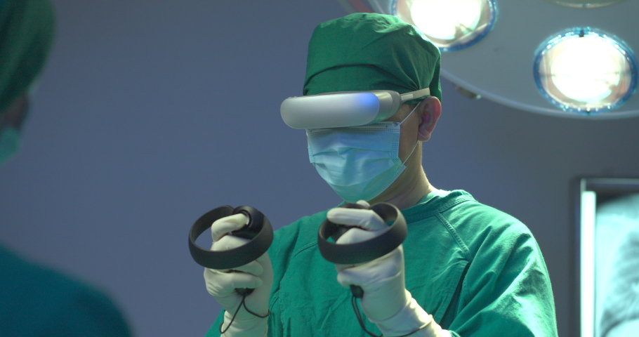 Team of surgeons wearing augmented reality headsets and using joysticks performing operation on a patient in operating theater at the hospital. Teamwork, Healthcare and medical technology concept. Royalty-Free Stock Footage #1067220901