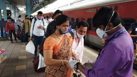 MUMBAI-INDIA - January 18, 2021: A health worker checks the body temperature of a passenger at Dadar station during COVID-19 testing drive.