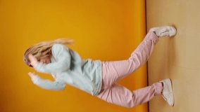 Vertical video of a woman dancer moving against yellow background in studio.