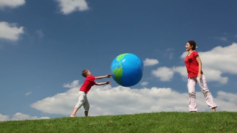mother and son playing with inflatable ball in meadow
